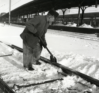 168603 Afbeelding van een wegwerker van de N.S. tijdens het ruimen van sneeuw bij een wissel van het N.S.-station ...